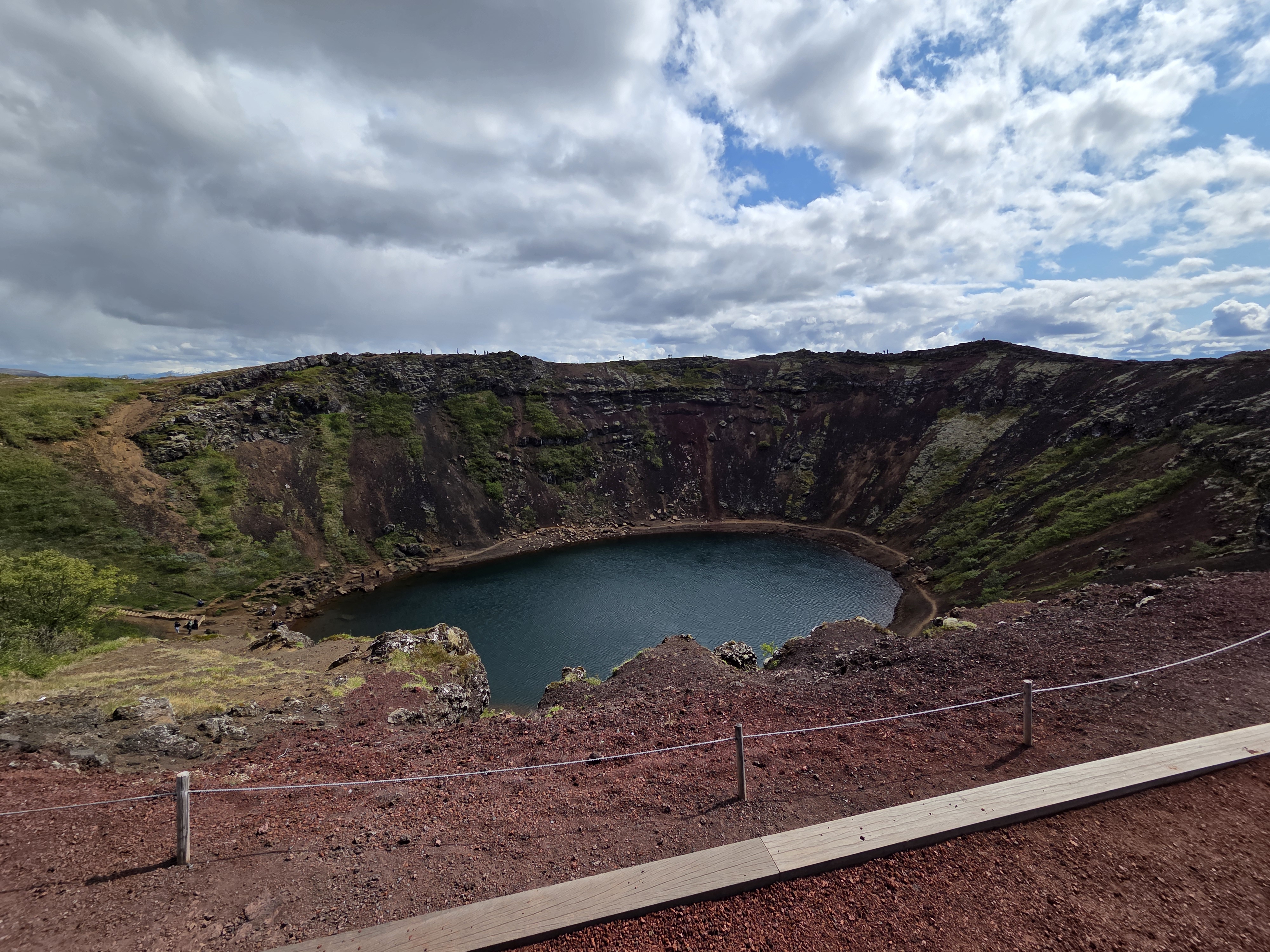 Kerið crater viewed from the rim with aquamarine lake and red volcanic rock